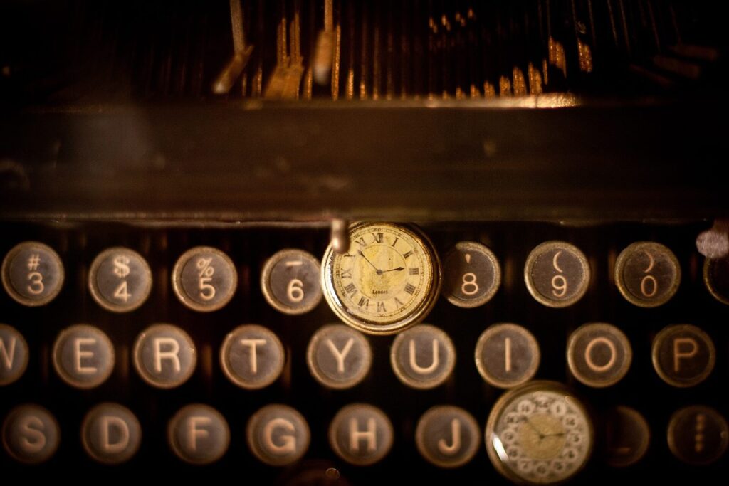 Teclas de una máquina de escribir antigua con dos relojes de bolsillo